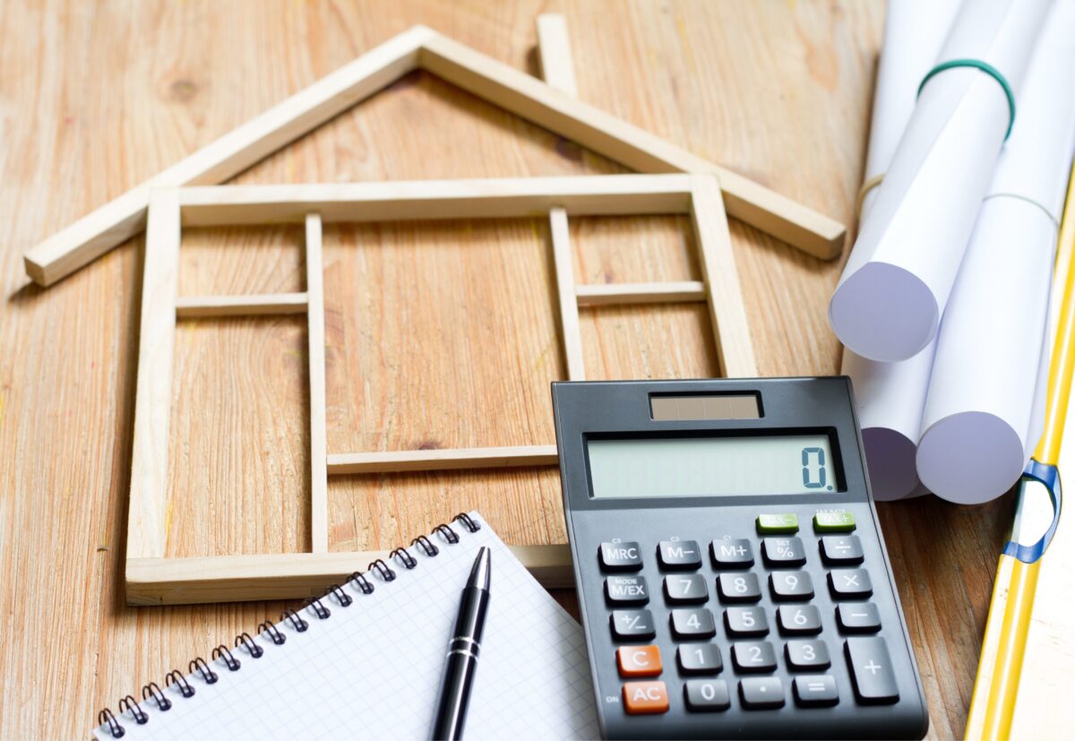 Calculatrice, plan de maison et carnet de notes sur une table pour estimer un crédit travaux en Belgique.